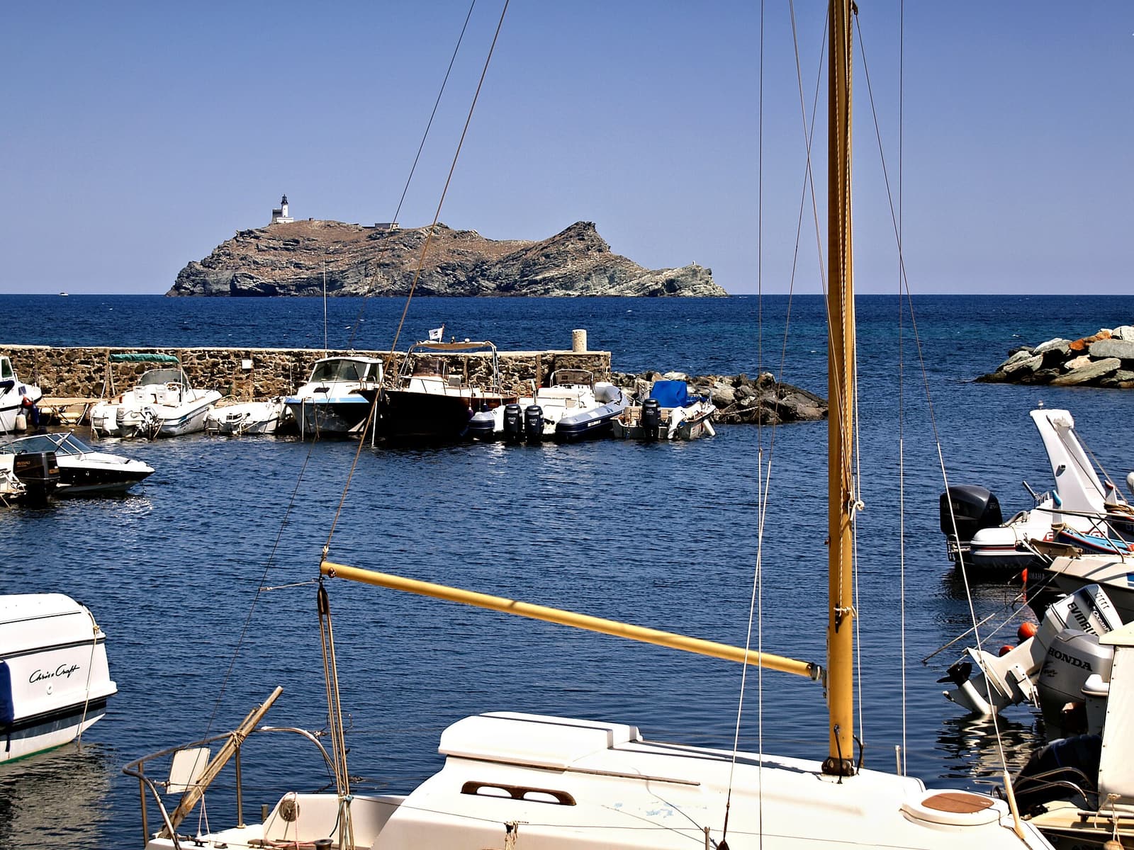 The small harbour of Barcaggio with the island of Giraglia and its lighthouse just offshore