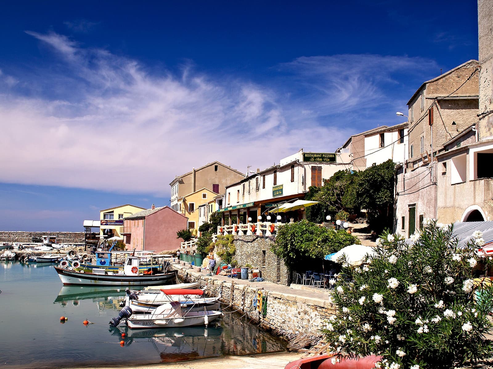 Fishing boats in the small harbour of Centuri, lined with restaurants and old stone houses