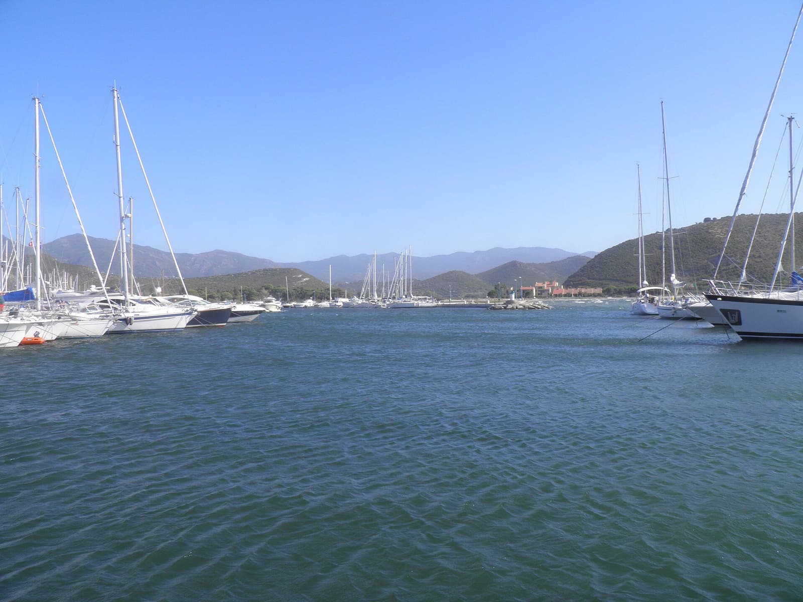 Sailing boats moored in the harbour of Saint-Florent with hills on the far side of the gulf