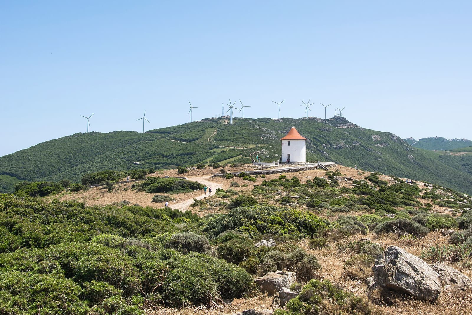The Moulin Mattei windmill on a ridge at the Col de la Serra, with wind turbines on the hills behind