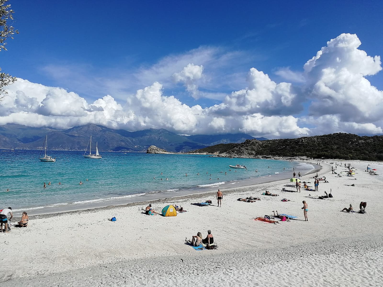 White sand, turquoise water and anchored boats at Lotu beach in the Agriates