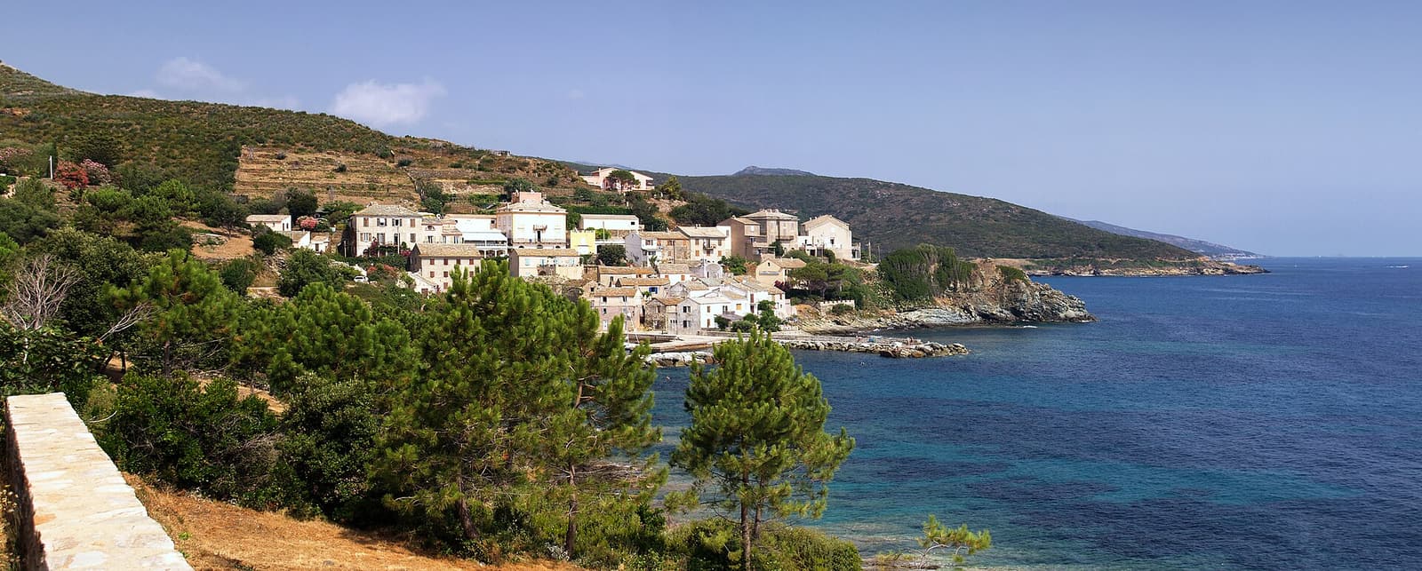 The small harbour hamlet of Porticciolo on the east coast of Cap Corse, seen across a blue bay
